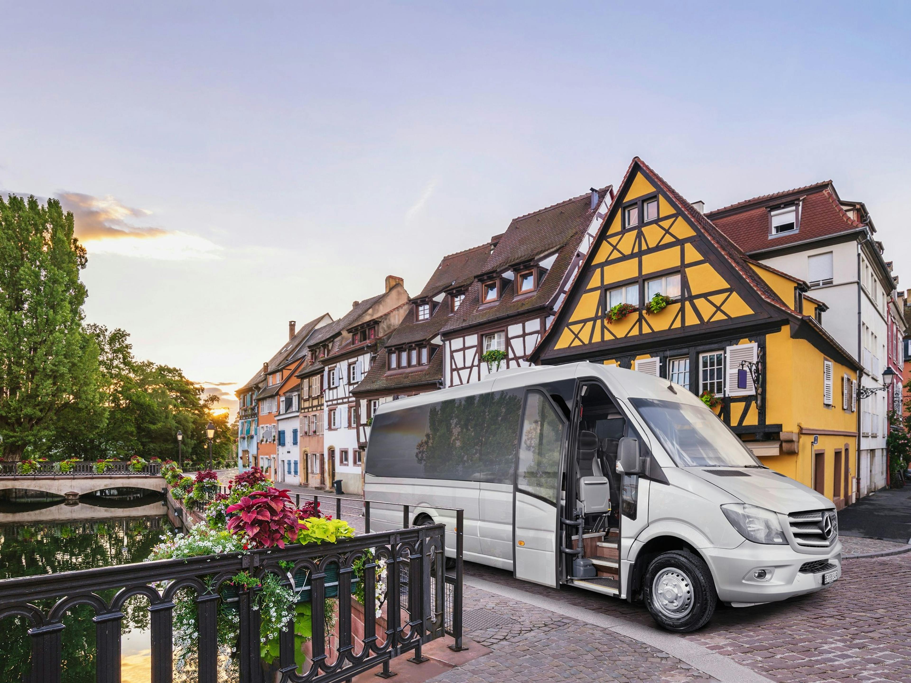 Colmar: Kleiner Bus vor malerischen Fachwerkhäusern im Herzen von Frankreich.