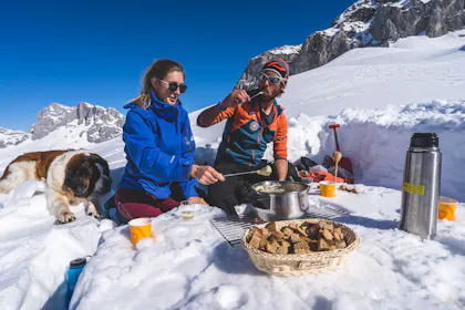 Fondue-Gipfel-Erlebnis im Schnee mit Freunden, winterliche Landschaft.