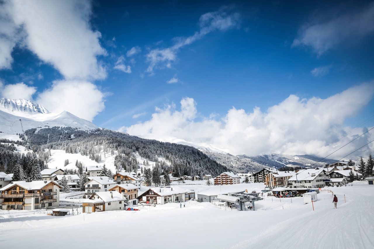 Lenzerheide Heimberg om vinteren med snedækkede bjerge, skiløbere og hytter.