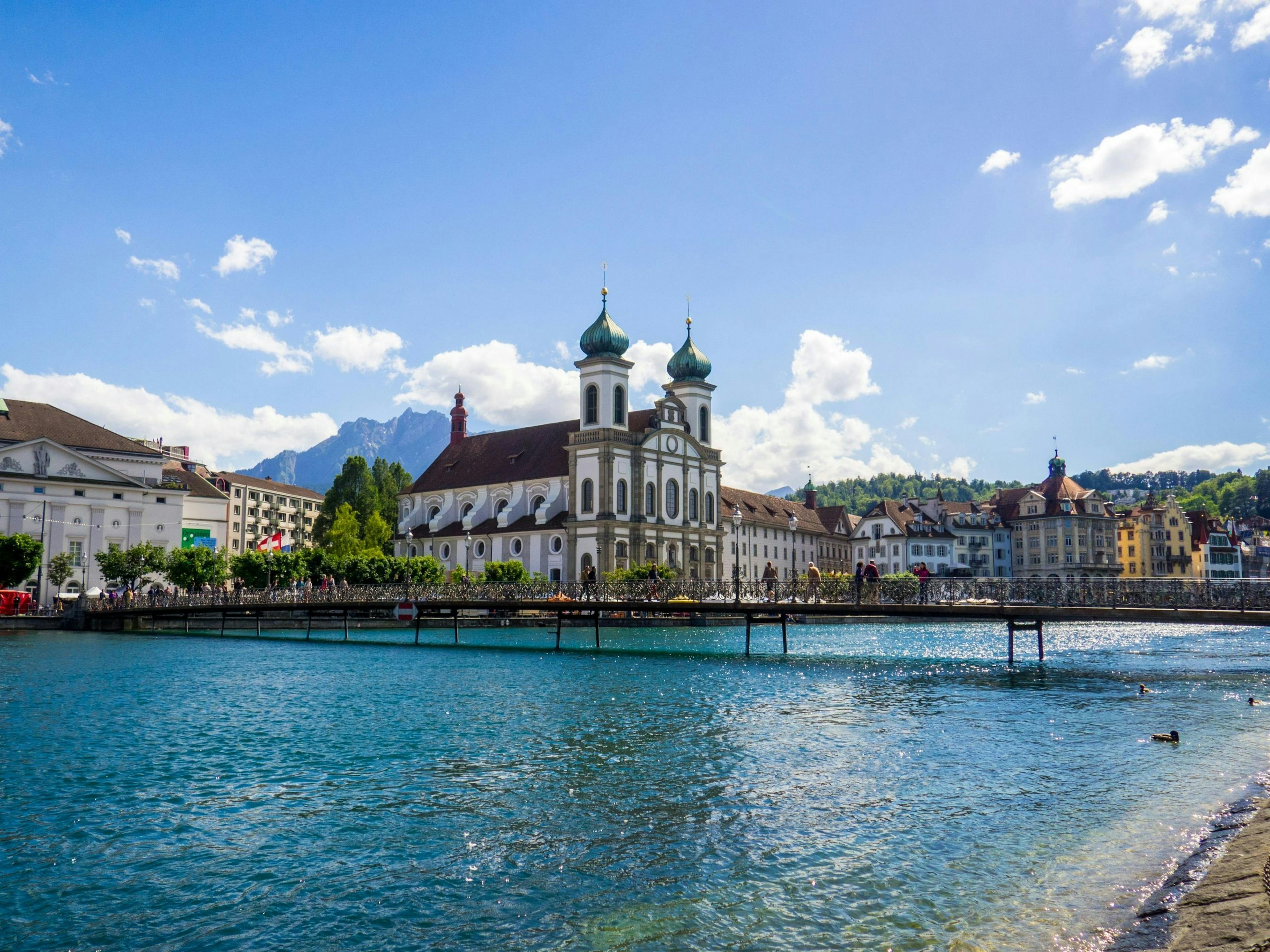 Lucerna: Vista da cidade à beira do lago com montanhas ao fundo, ideal para passeios de verão.