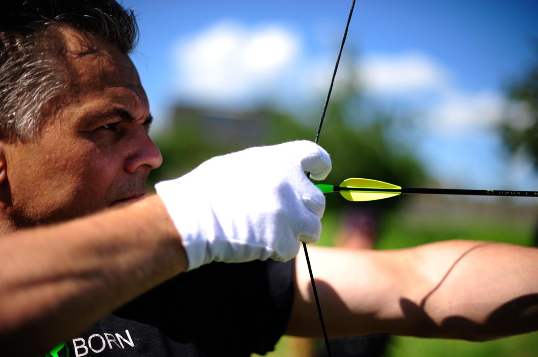Стрельба из лука в Швейцарии: мужчина натягивает стрелу в солнечной обстановке
