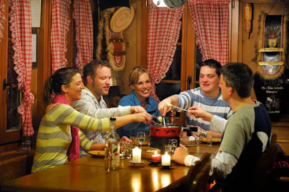 Menschen geniessen ein gemütliches Abendessen in einer Hütte.