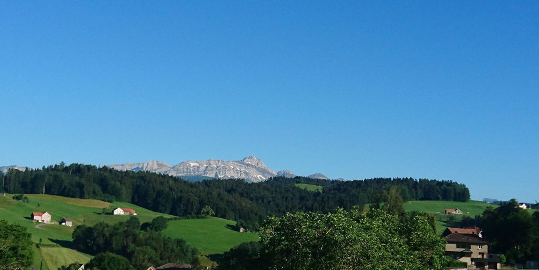 Paisagem montanhosa em Sylt com visibilidade clara, campos verdes, céu azul.