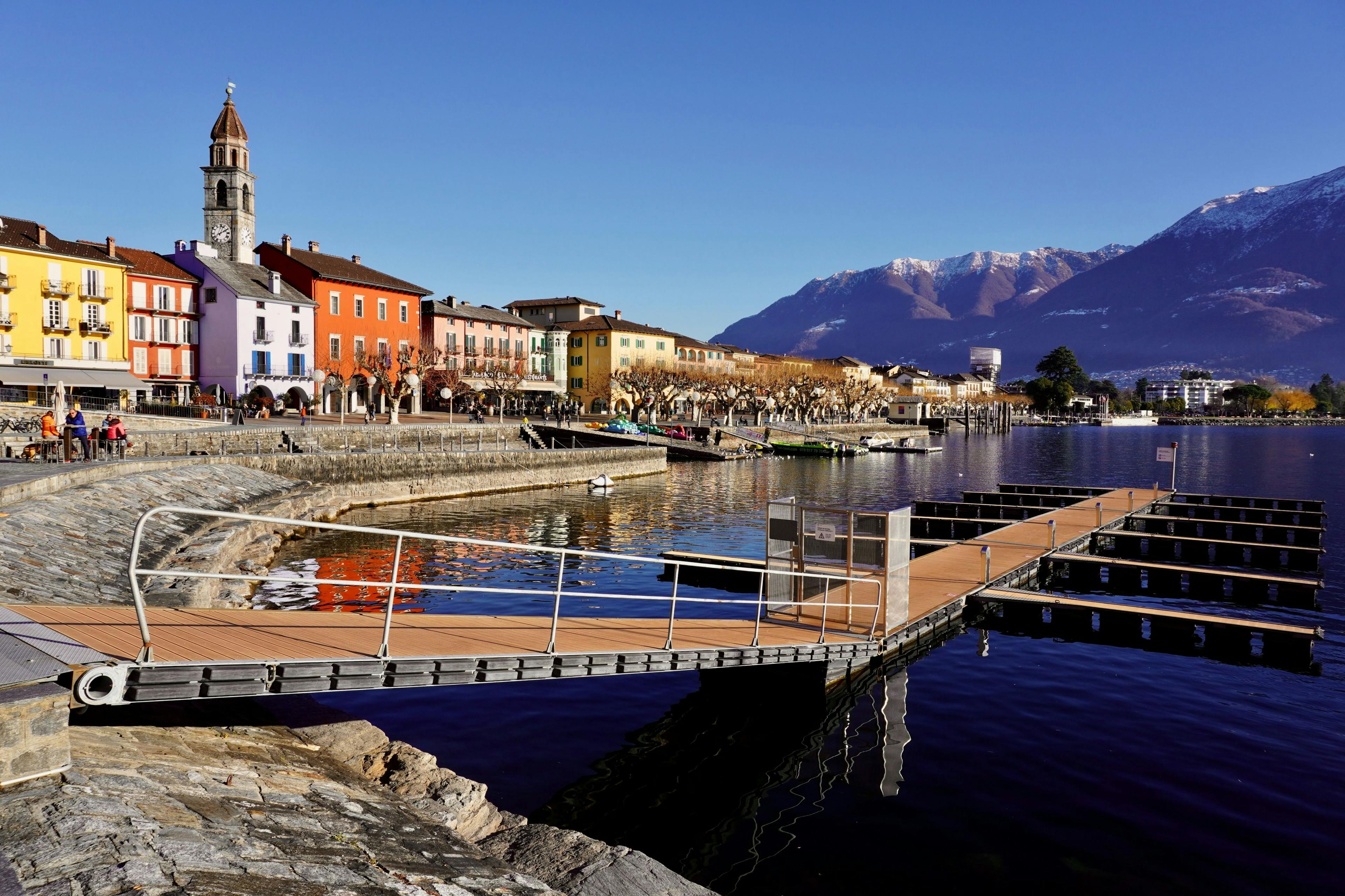 Ascona : Promenade pittoresque avec des bâtiments colorés et des montagnes en arrière-plan.