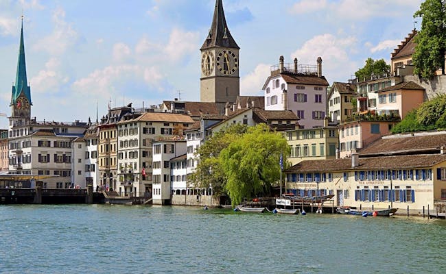 Limmat River in Zurich with historic architecture and classic boats in the water.