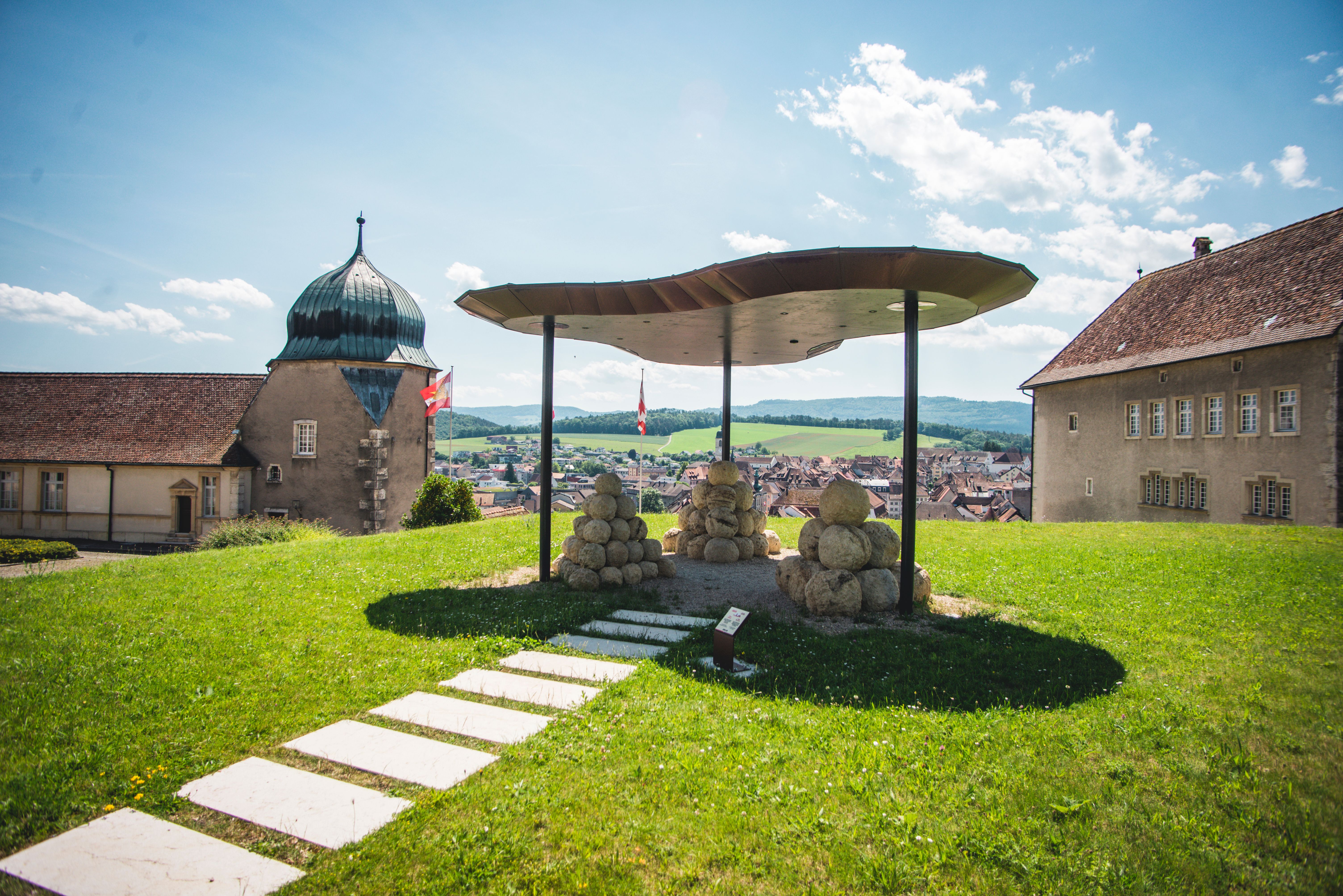 Μονοπάτι Μυστικό Πορνετρούι: ειδυλλιακό τοπίο με ιστορικό κτίριο και καλλιτεχνική εγκατάσταση.