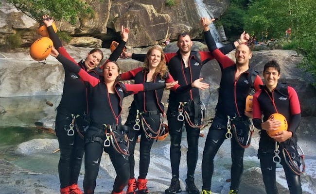 Canyoning Boggera con gruppo, divertimento e avventura. Tute in neoprene colorate, cascata sullo sfondo.