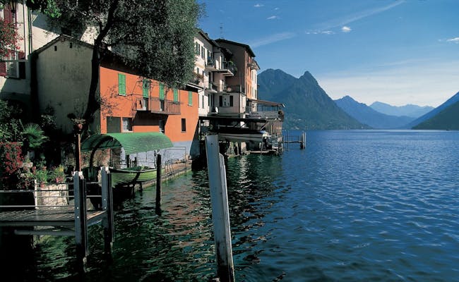 Luganersee med hus, vatten och berg i bakgrunden