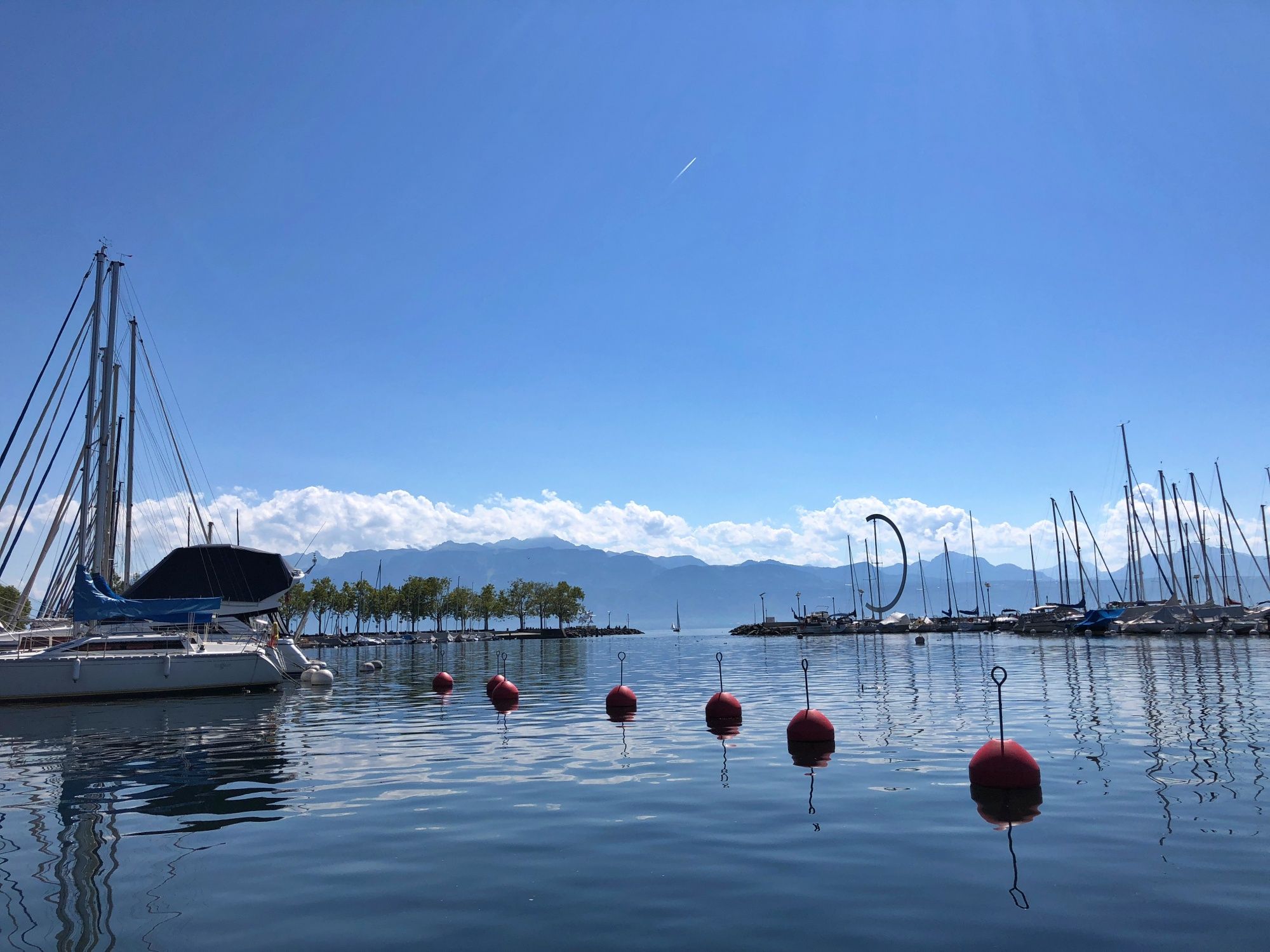 Porto de Lausanne com barcos, vista para o lago e as montanhas, ideal para atividades de verão na água.