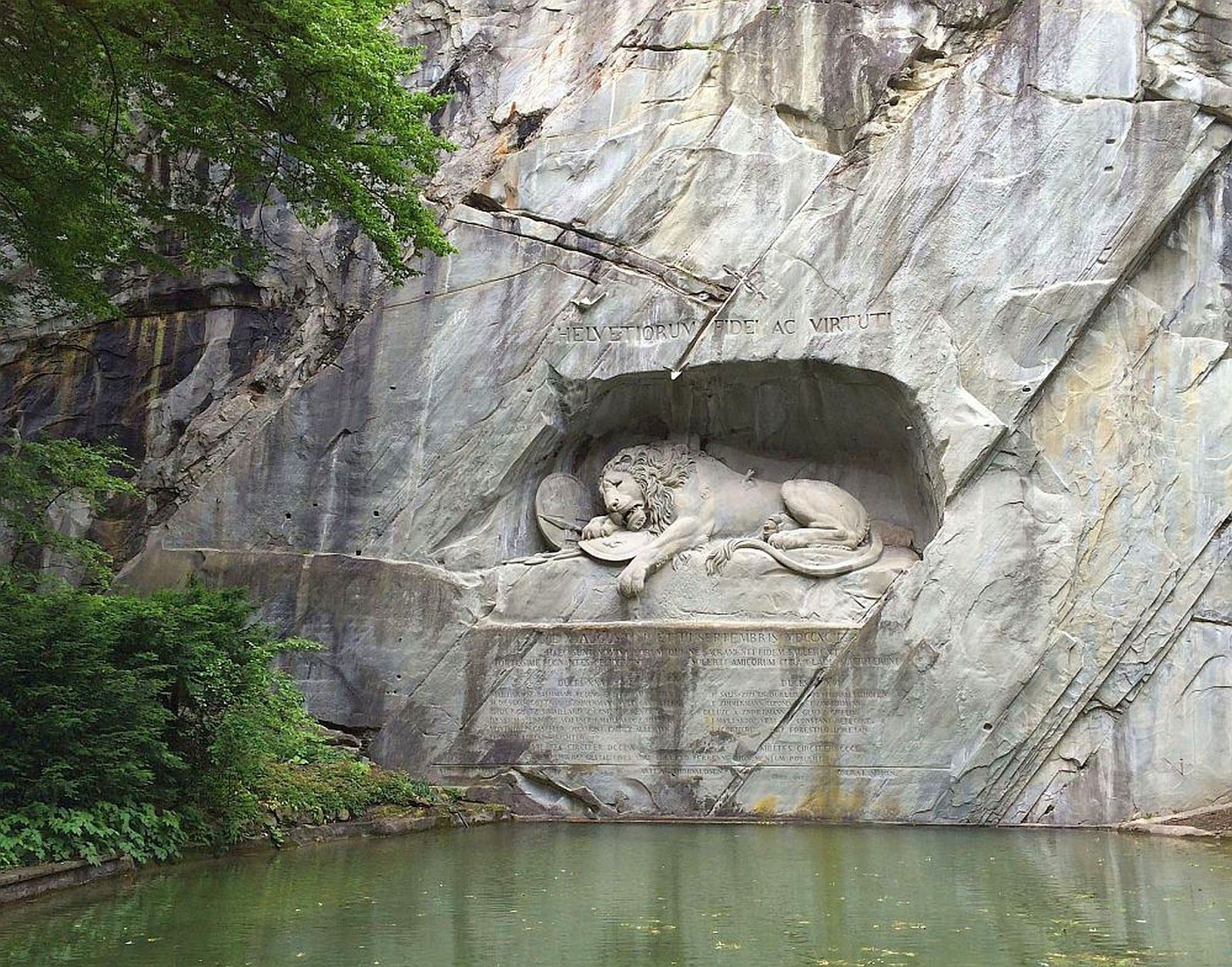 Löwendenkmal: beeindruckende Statue des sterbenden Löwen in Luzern, umgeben von Natur und Felsen.