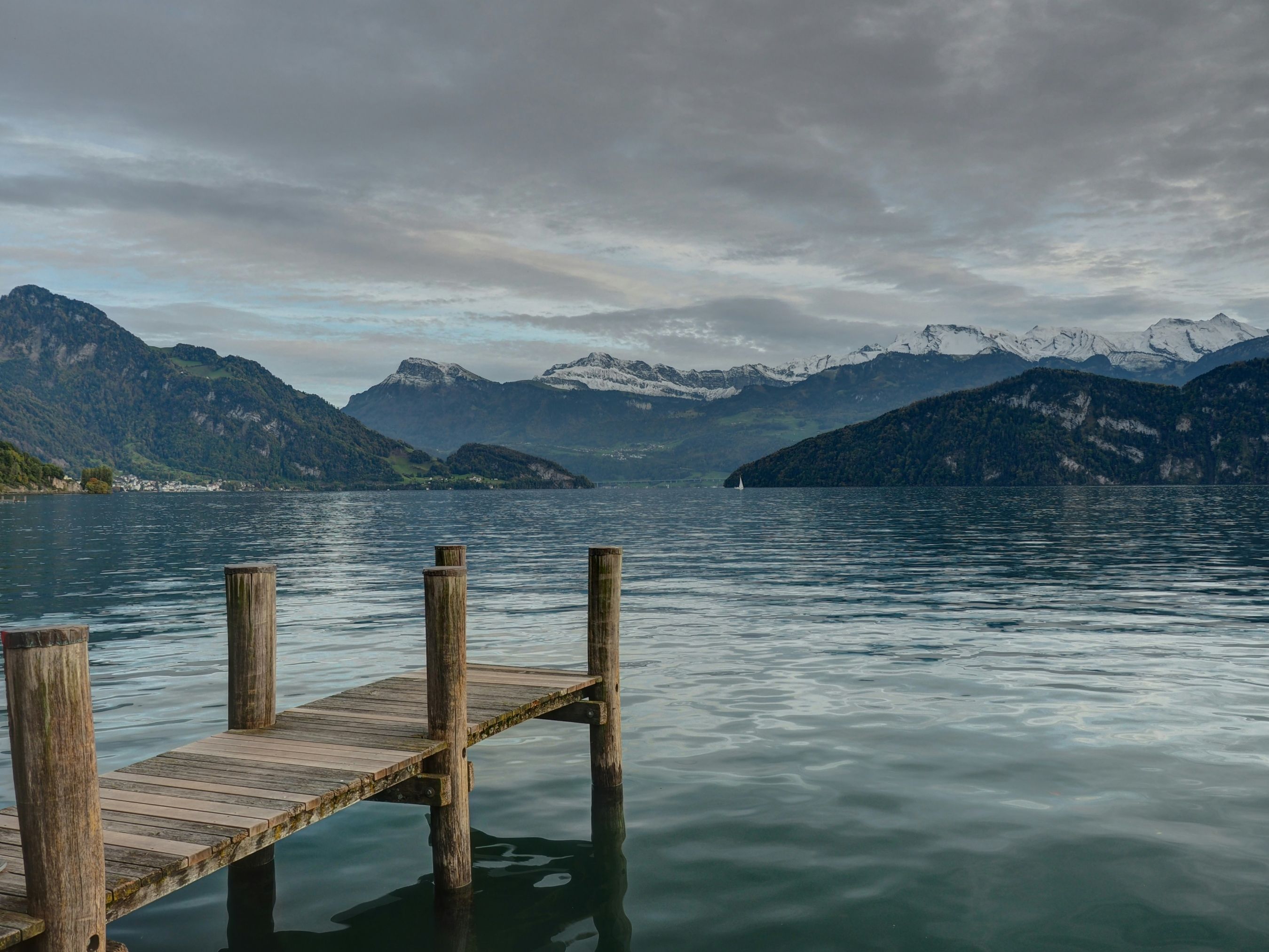 Lucerna: lago tranquillo con pontile in legno e montagne innevate sullo sfondo. Luogo ideale per gli amanti della natura.