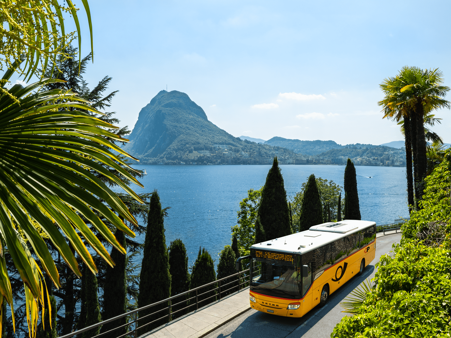 حافلة بريدية على بحيرة لوغانو في تيسينو مع إطلالة على جبل بري، مثالية لنزهات مريحة.