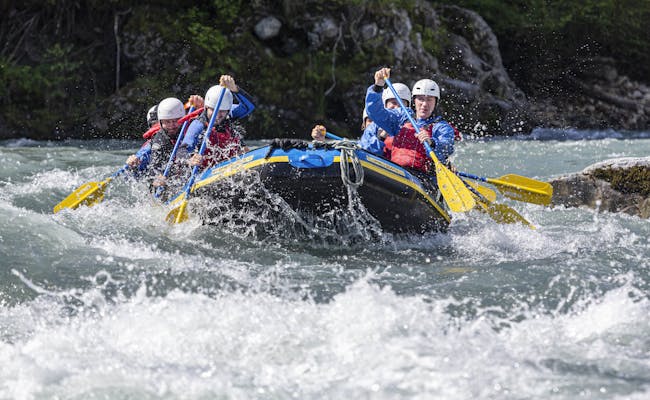 Rafting di Vorderrhein dengan peserta mengenakan perlengkapan biru di air yang deras