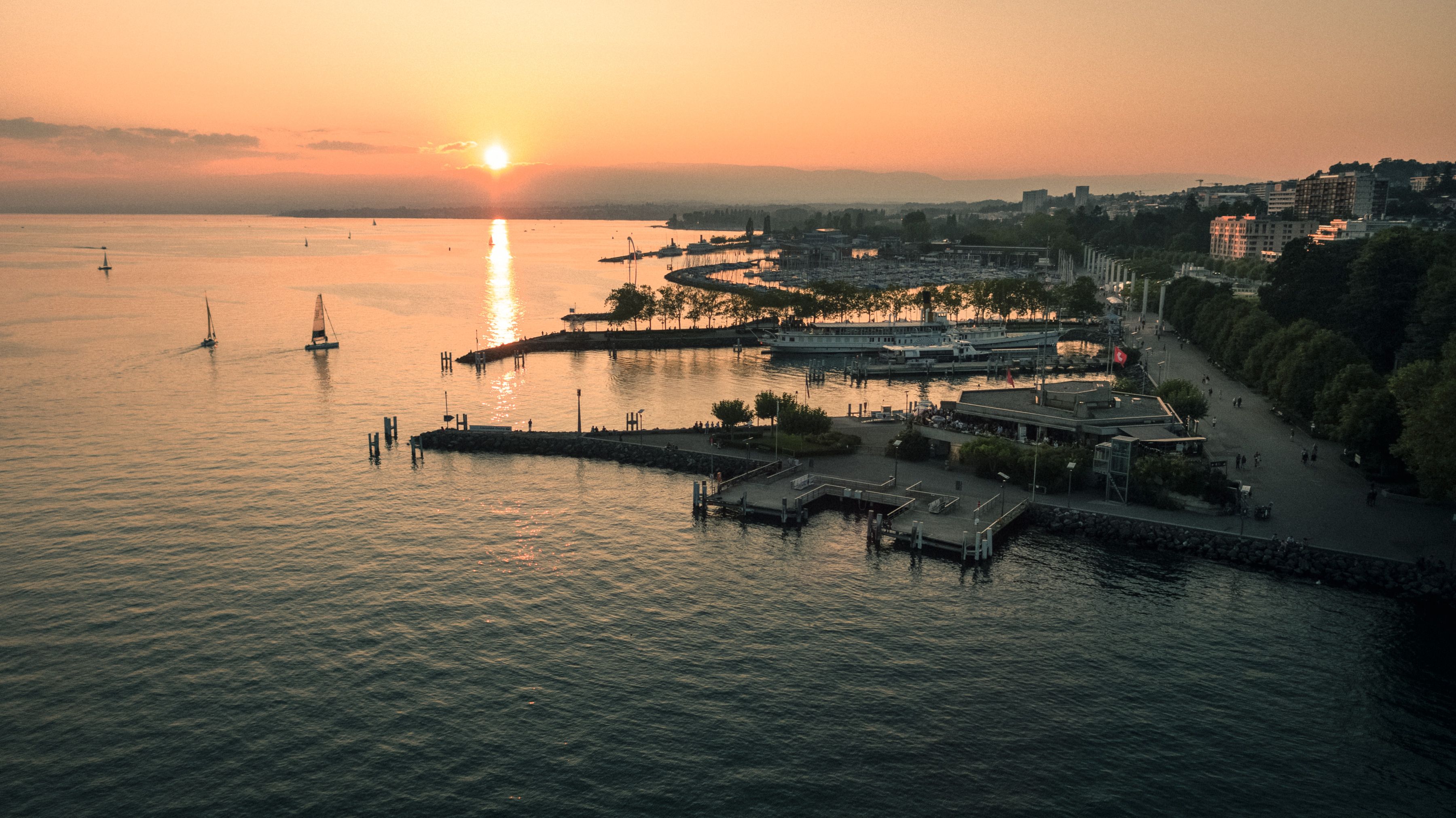 Lake Geneva: picturesque sunset over the lake with boats and promenade in Switzerland.