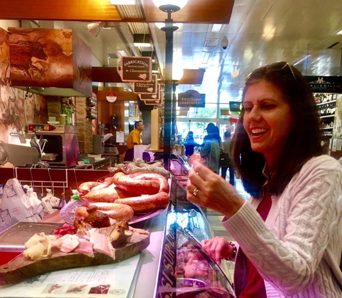 Donna prova la salsiccia al bancone di una macelleria