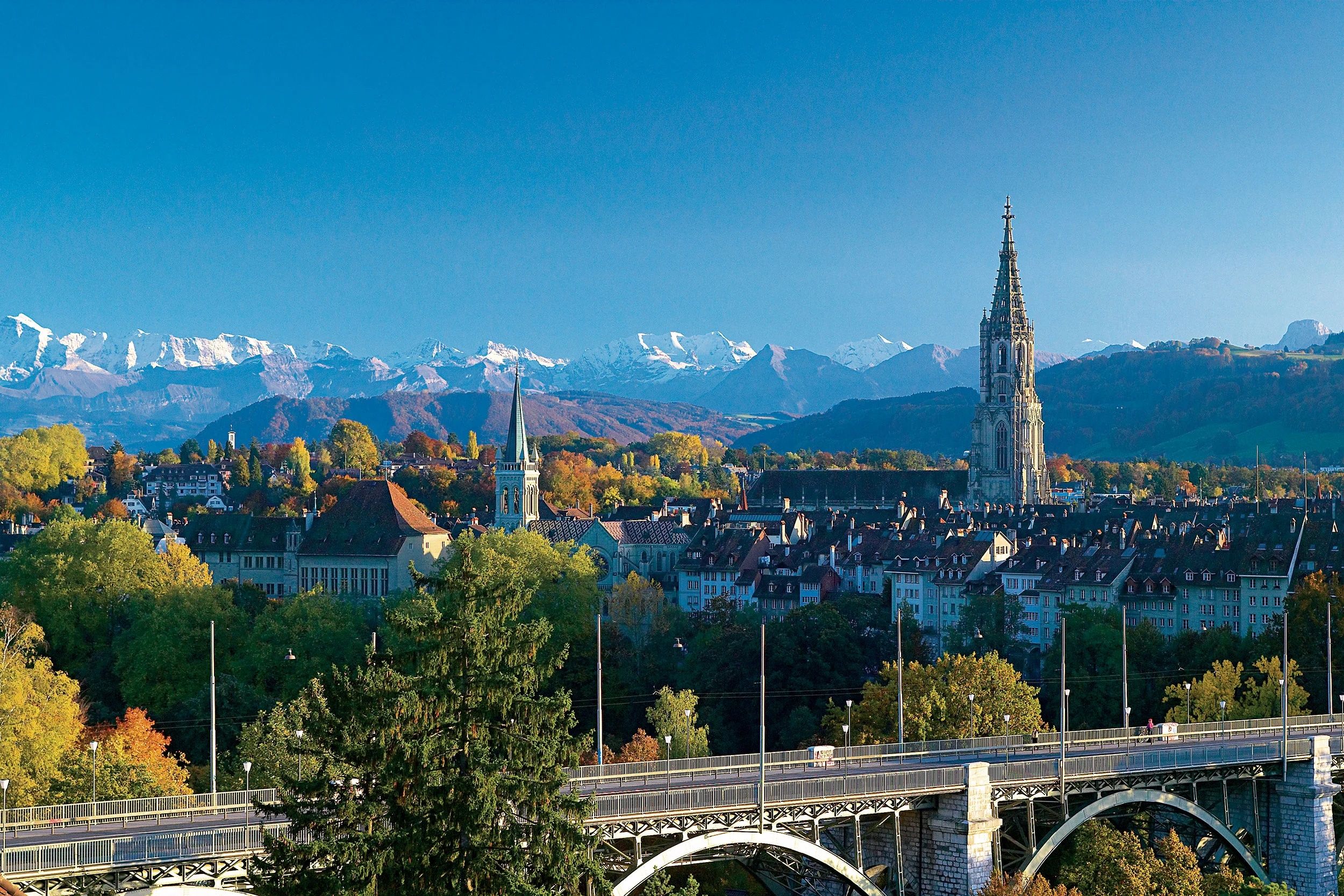 Vue sur Berne avec paysage urbain, montagnes et couleurs d'automne éclatantes. Découvre la beauté de la capitale.