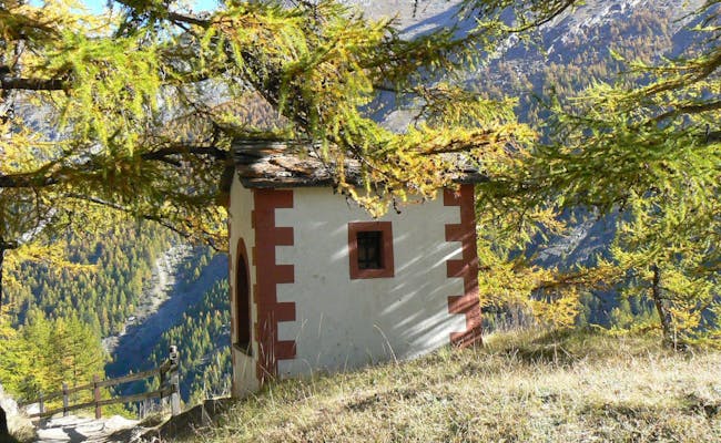 Kapellenweg v Saas-Fee, tradiční kaple obklopená jedlemi.