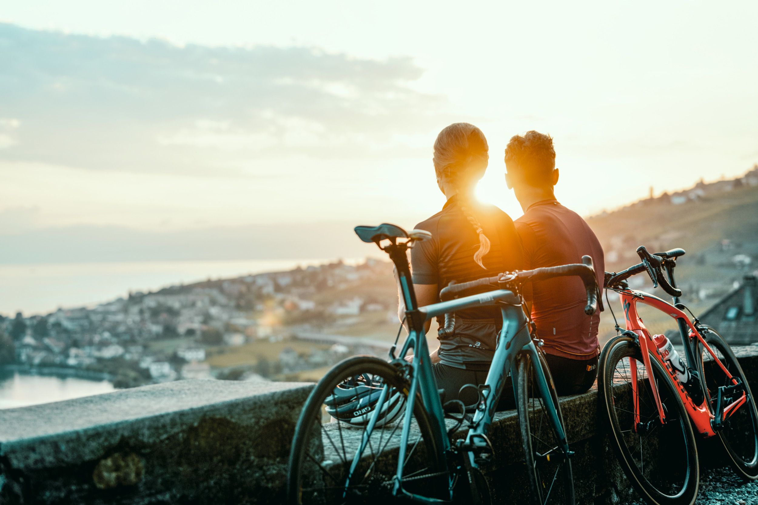 Cykloturistika s výhledem na západ slunce nad Švýcarskem, cyklisté si užívají krajinu.