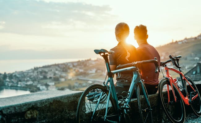 Tour en bicicleta con vista al atardecer sobre Suiza, ciclistas disfrutan del paisaje.