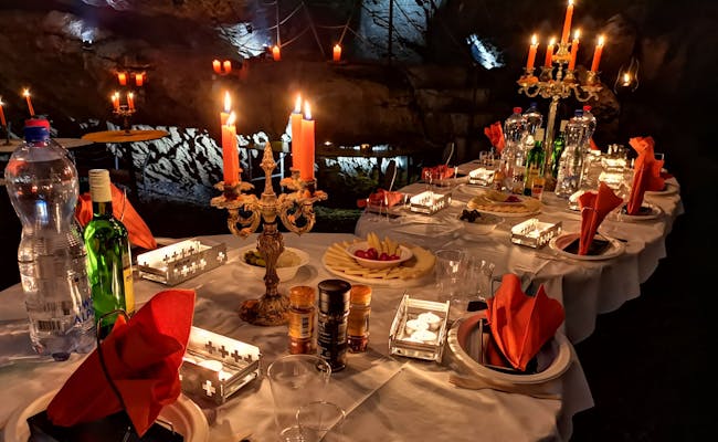 Raclette i grotten Hölloch ved en festlig opsætning, stearinlys og hyggelig atmosfære.