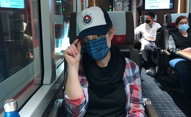 Person med hue og mundbind på Glacier Express