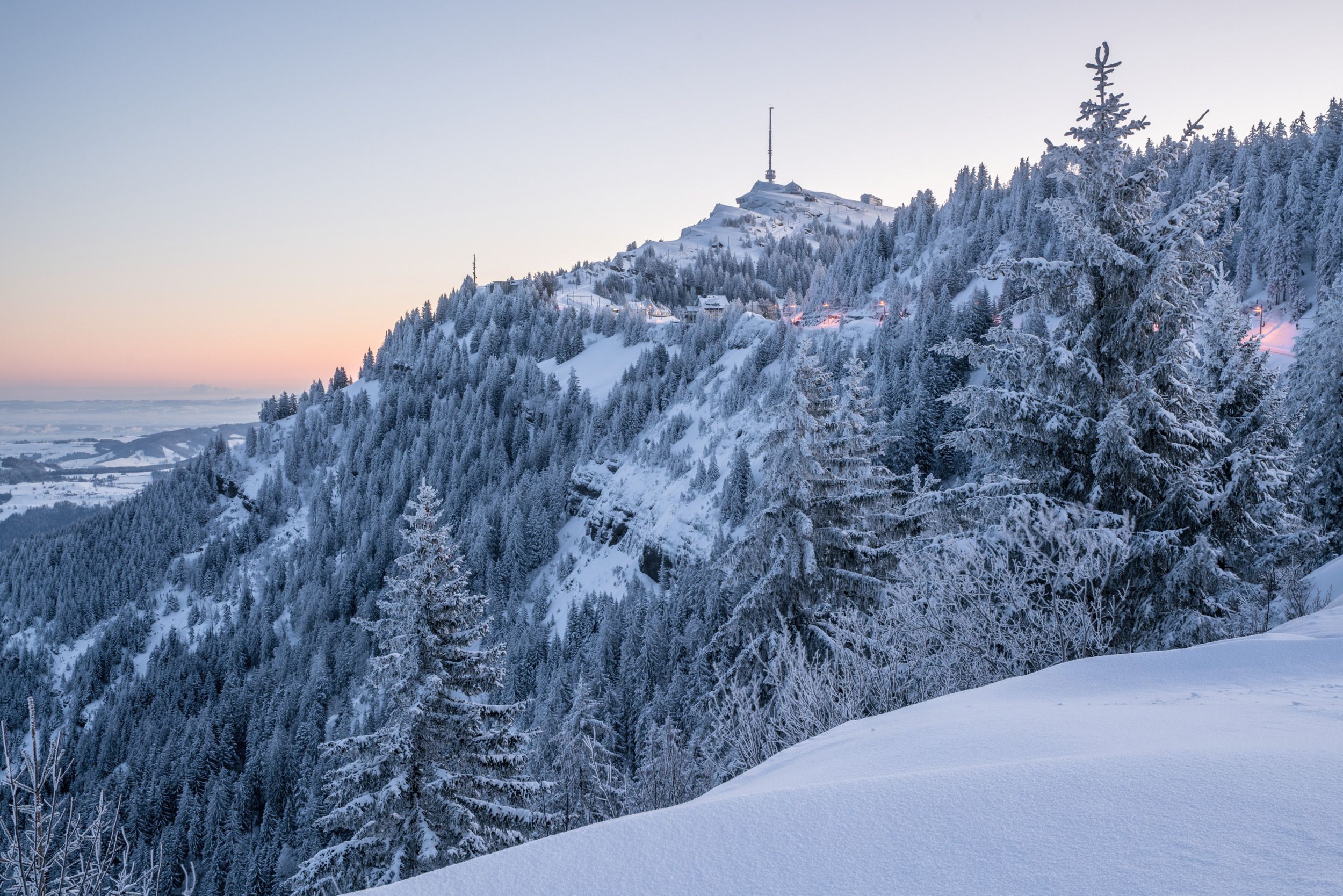 Paisagem de inverno na Suíça com montanhas cobertas de neve e pinheiros, ideal para esportes de neve e magia natalina.