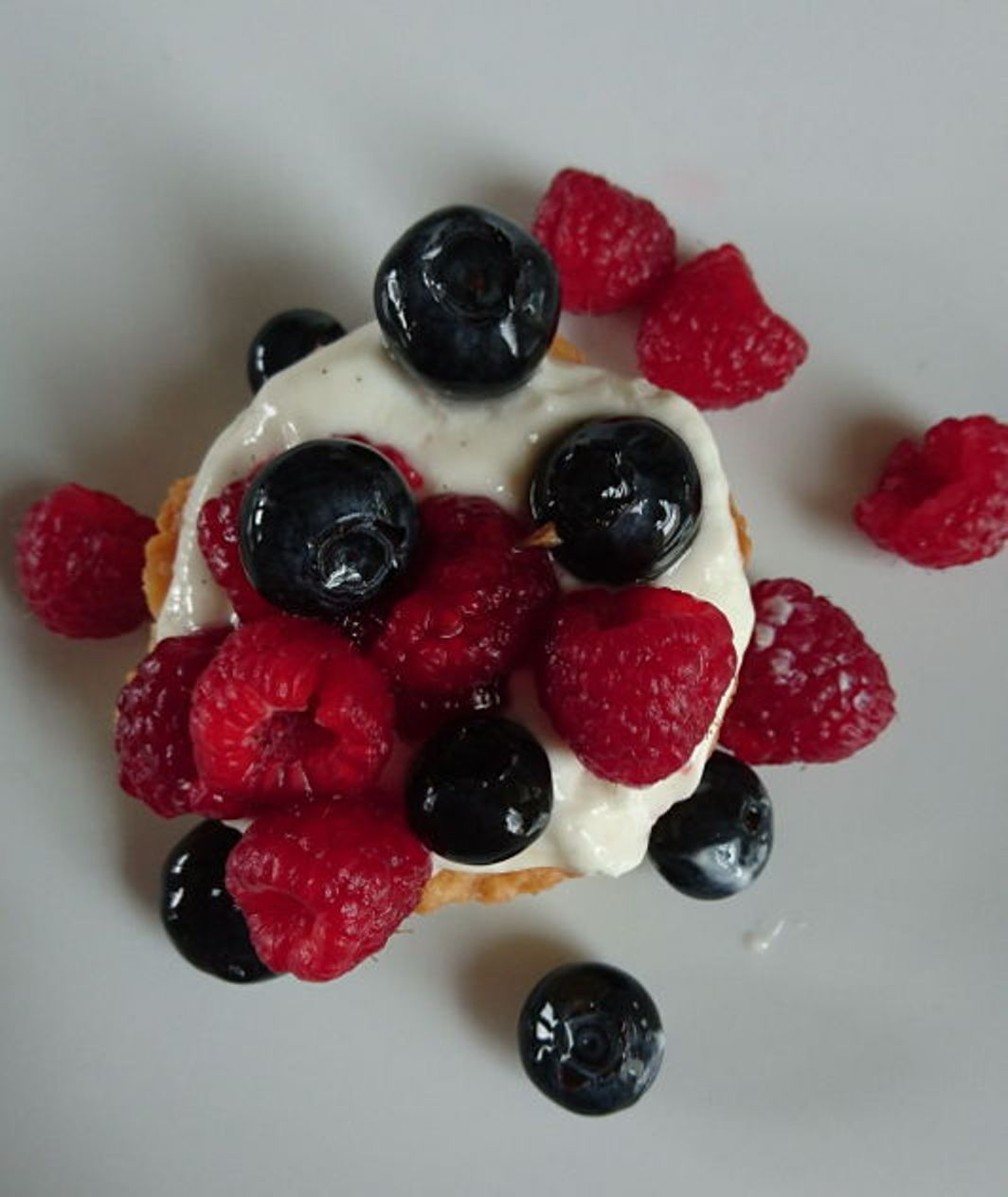 Torta de frutas com framboesas e mirtilos frescos, decorada com natas.