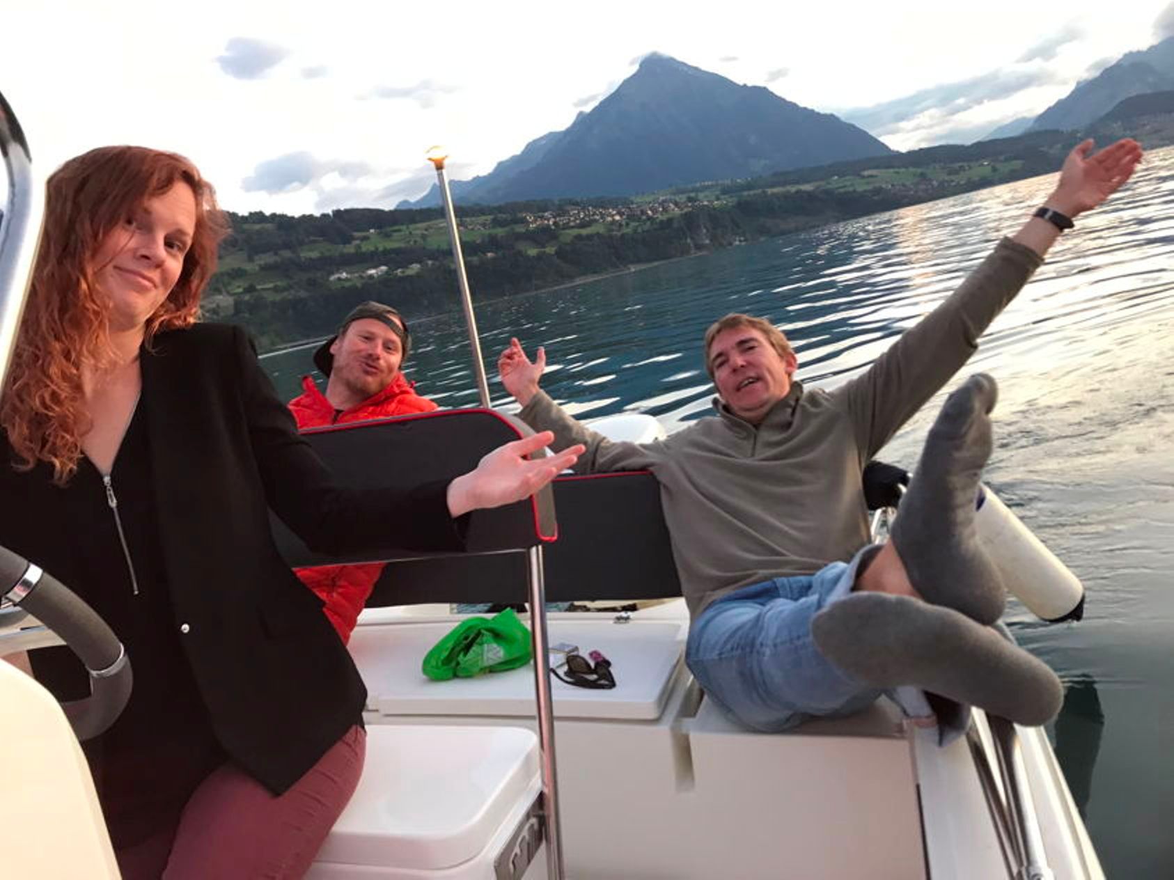 사람들이 호수에서 산을 배경으로 치즈와 와인을 곁들인 보트에서 휴식을 취하고 있다.