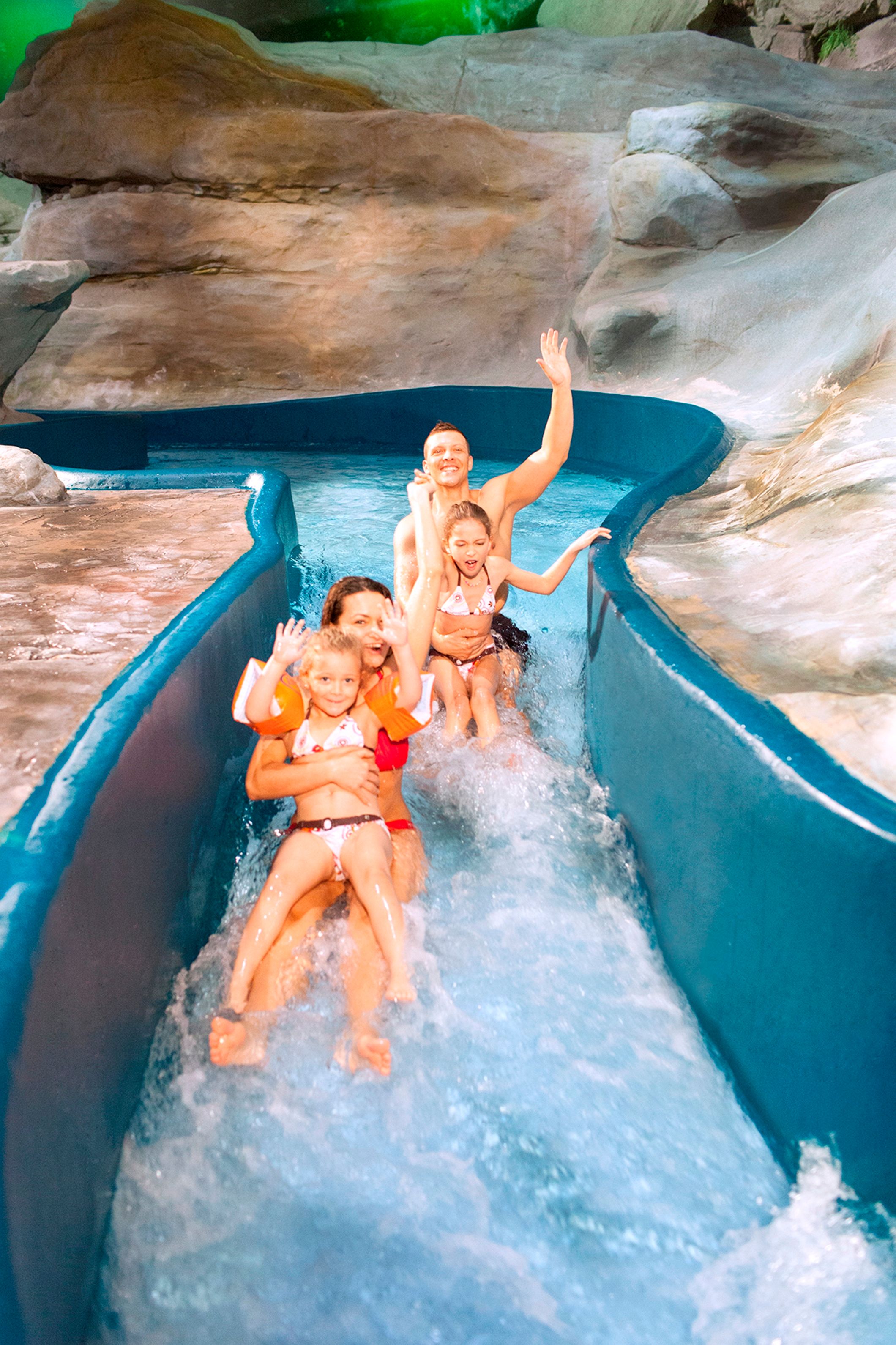 Water park Aquabasilea, family happily sliding down the slide