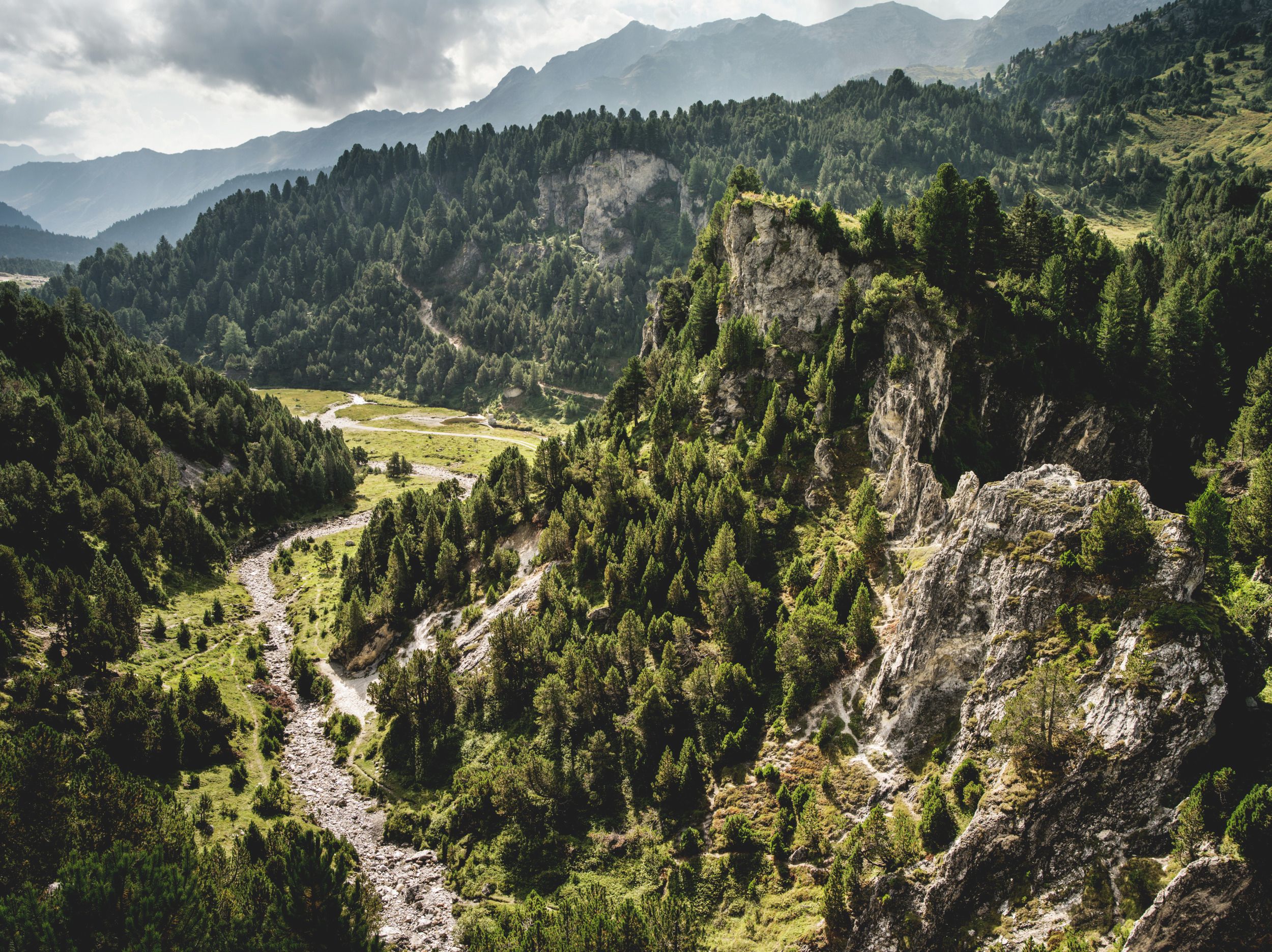 بلاينيو لوكمانيير باس: منظر جبلي مذهل في سويسرا مع غابات خضراء ونهر.