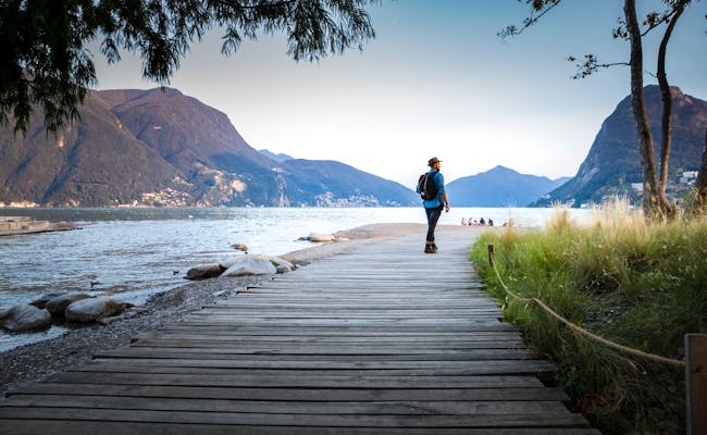 Lugano Foce del Cassarate: Paseante en la orilla del lago en verano con montañas al fondo.