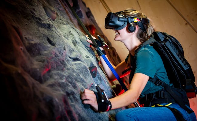 The Edge no Museu dos Transportes de Lucerna, mulher a escalar com equipamento de VR numa parede de escalada.