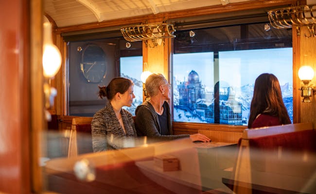 Jungfraubahn: Entspanne im historischen Wagen mit Blick auf die alpine Winterlandschaft und die Berge.