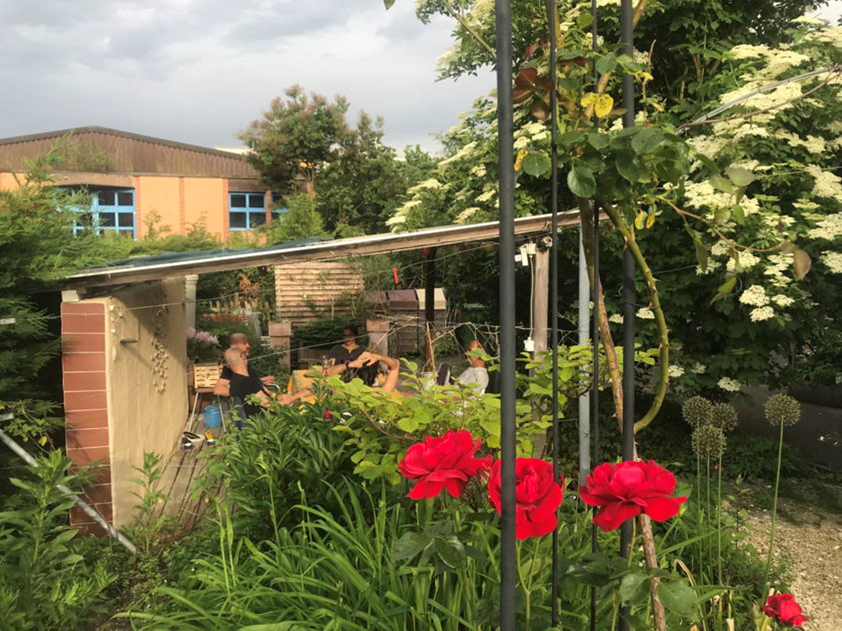Nachmittags-Snack im Garten, Personen sitzen im Grünen, entspannte Stimmung.