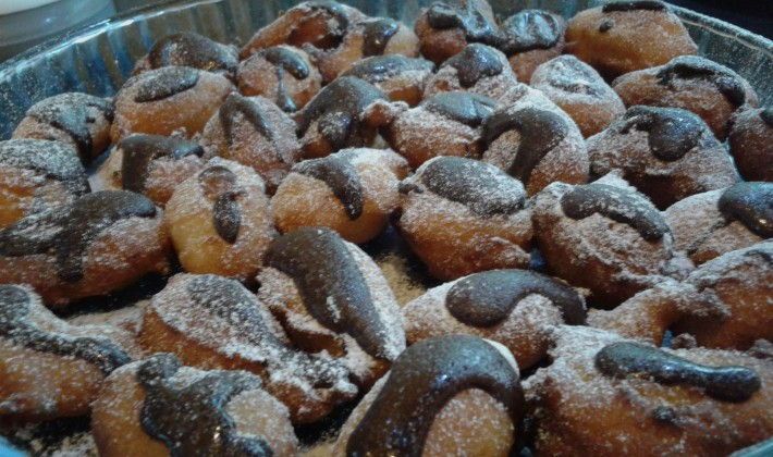 Sicilian pastry with chocolate glaze and powdered sugar on a baking tray.