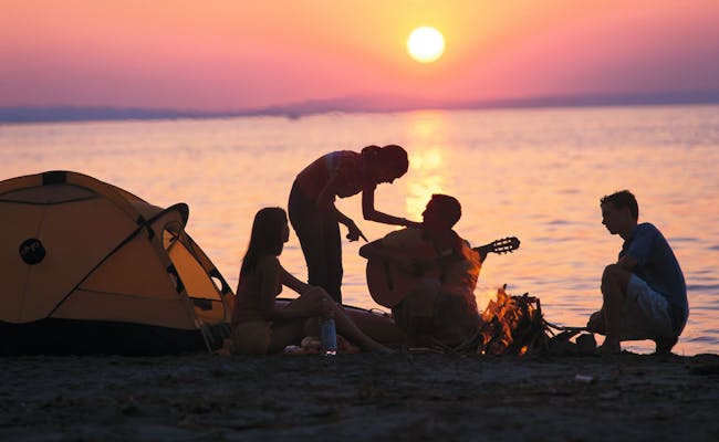 Kamperen bij zonsondergang met vrienden, tent aan het meer en een ontspannen sfeer