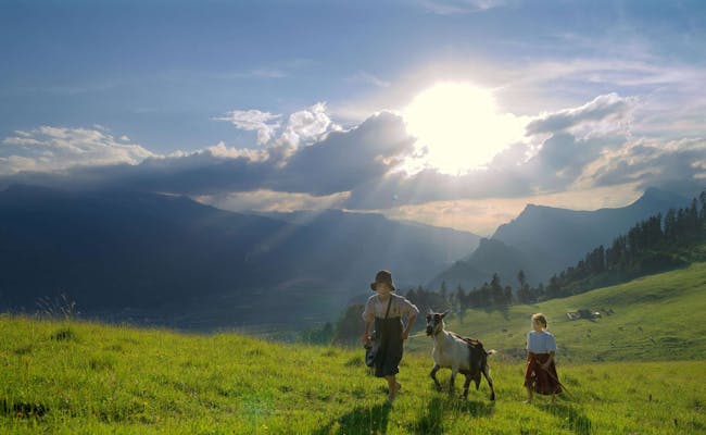 Heididorf con Heidi y Peter, que llevan la cabra en el prado, en los Alpes.