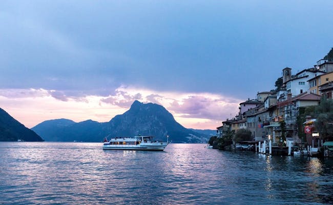 Lugano med båt i hamnen vid solnedgången