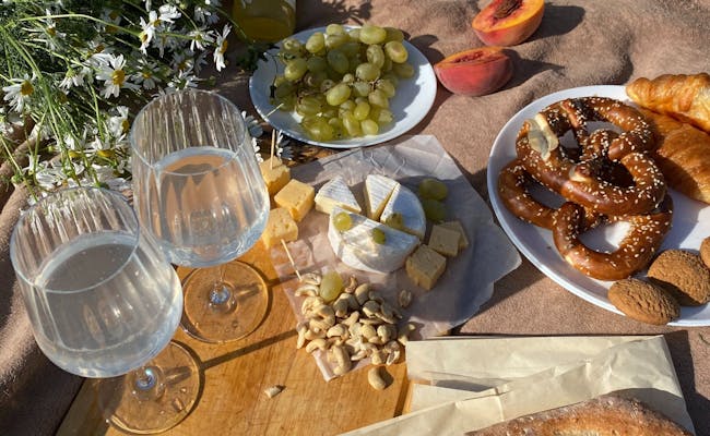 Picnic con formaggio, uva e bevande su una coperta.