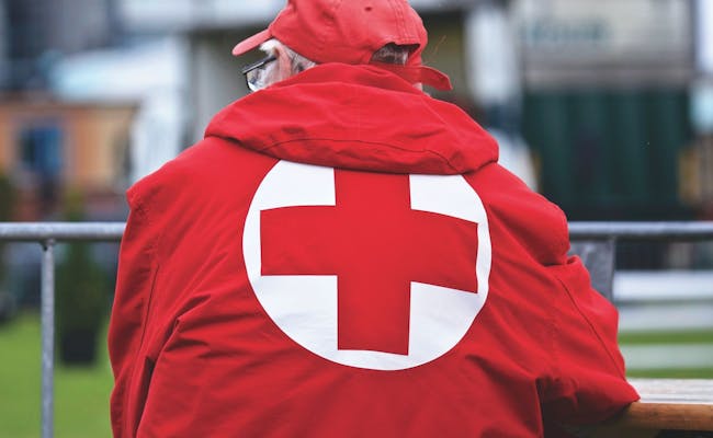 Personne en manteau rouge de la Croix-Rouge observe un festival
