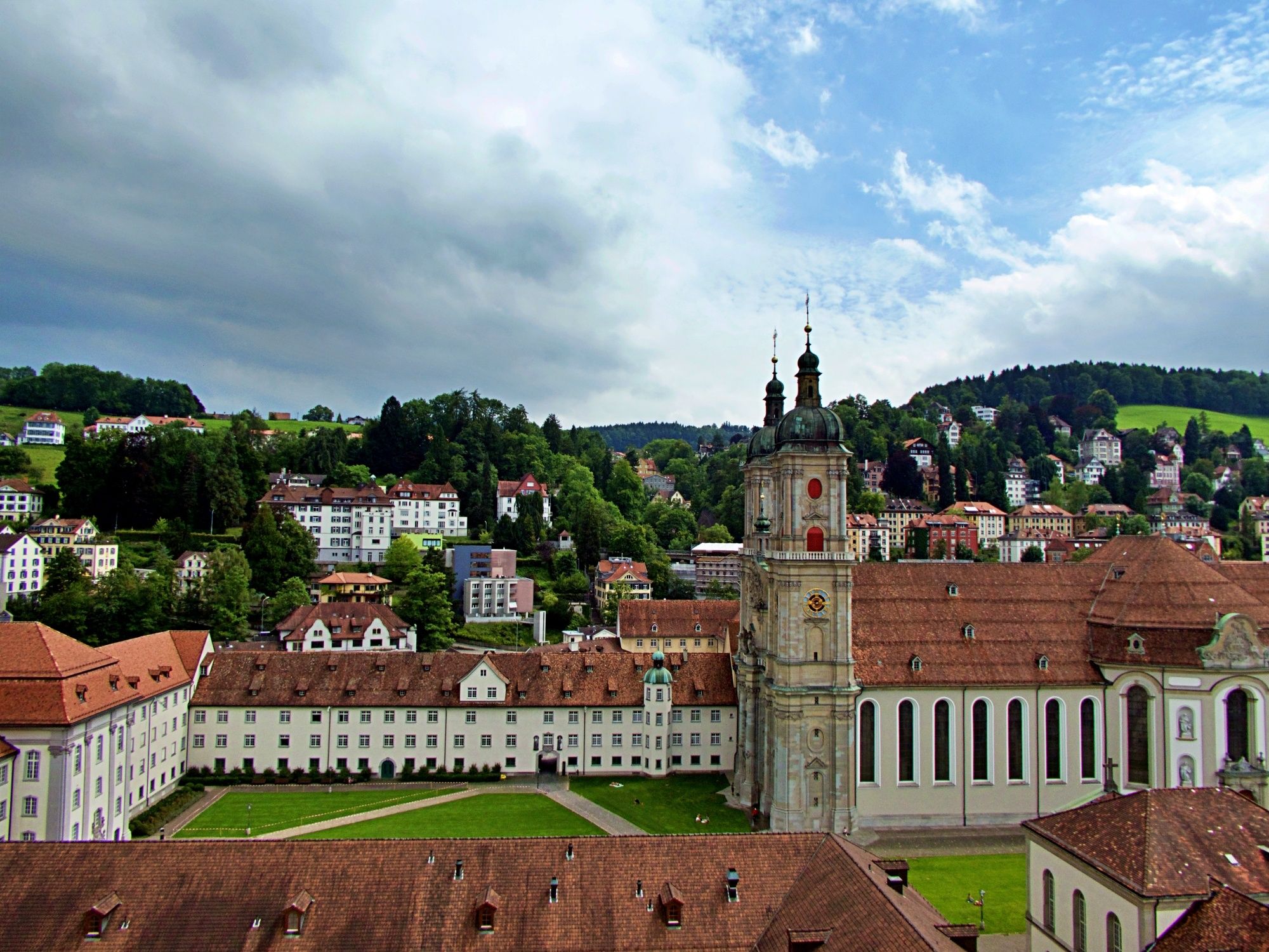 St. Gallen Abbey District with buildings and church, green landscape in the background.