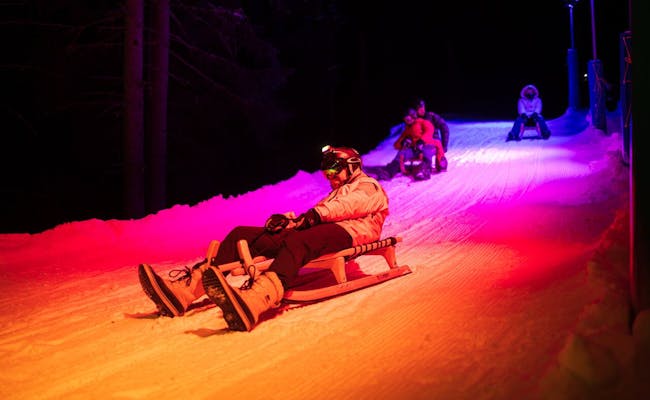 Light Ride Aankomst in Lenzerheide 's Nachts, bestuurder op de slee, verlichte piste.