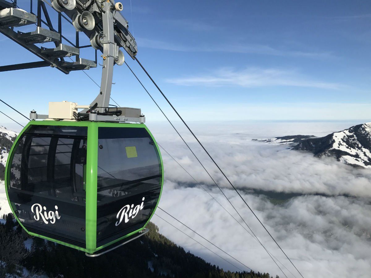 रिगी क्रैबल एयरलिफ्ट सुरंग पर बादल के ऊपर पर्वतों के साथ उड़ रहा है