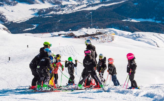 Barnskidåkning i St. Moritz med färgglada skidadyner på backen