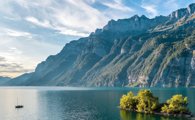 Walensee con bote y montañas circundantes, agua tranquila y árboles verdes