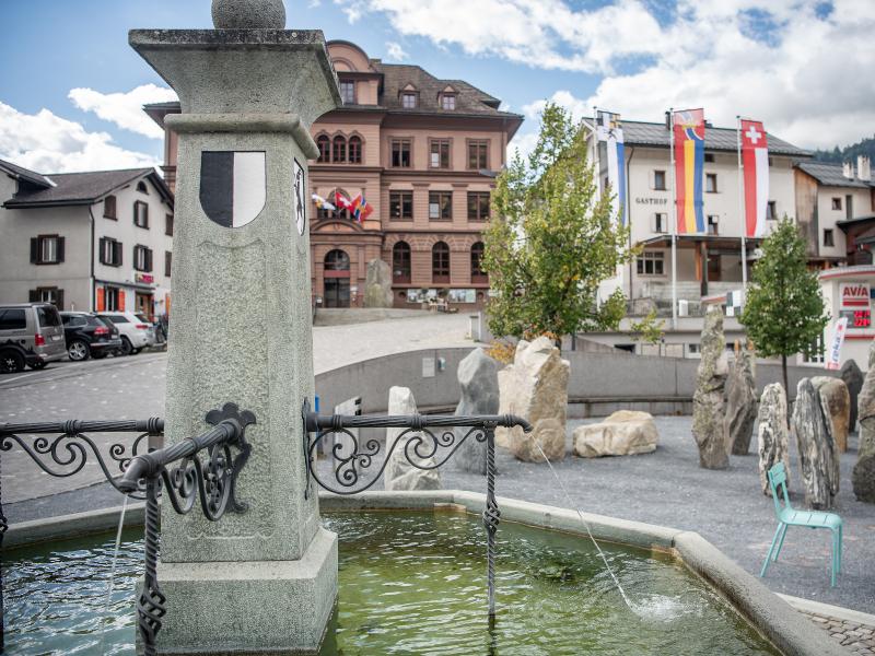Plazza Cumin: Brunnen mit historischem Gebäude in Ilanz, Sehenswürdigkeit, Stadtführung, Surselva.