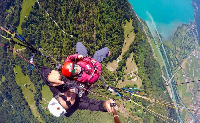 Vuelo en parapente en Interlaken con pasajero y piloto sobre un paisaje verde