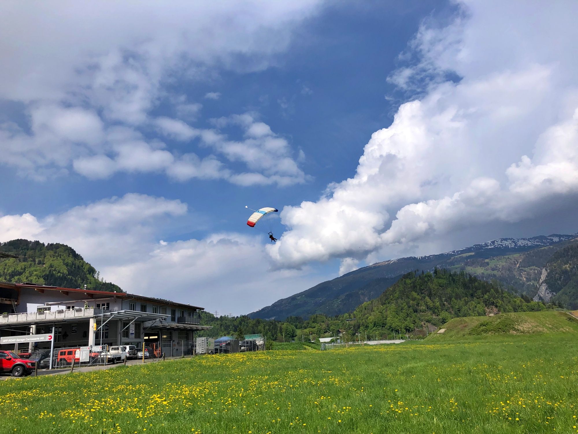 Skydive Interlaken กับการโดดร่มเหนือทุ่งหญ้าเขียวและภูเขาเป็นฉากหลัง
