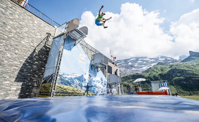 Sportler springt in Wasserbecken vor Bergkulisse im Sommer