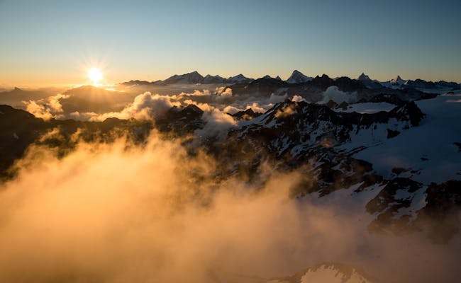 Mont Fort bei Sonnenaufgang mit schneebedeckten Gipfeln und Wolken